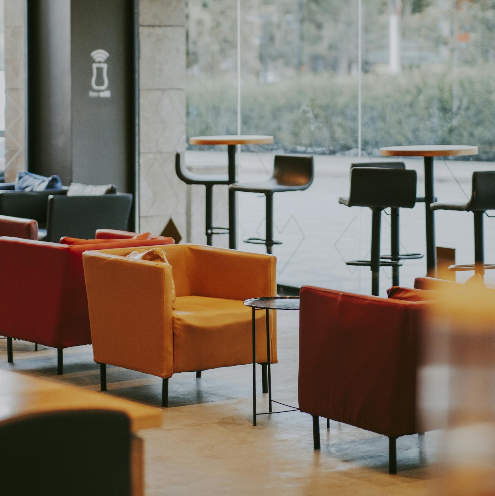 Modern café with vibrant armchairs and glass windows creating a bright atmosphere.