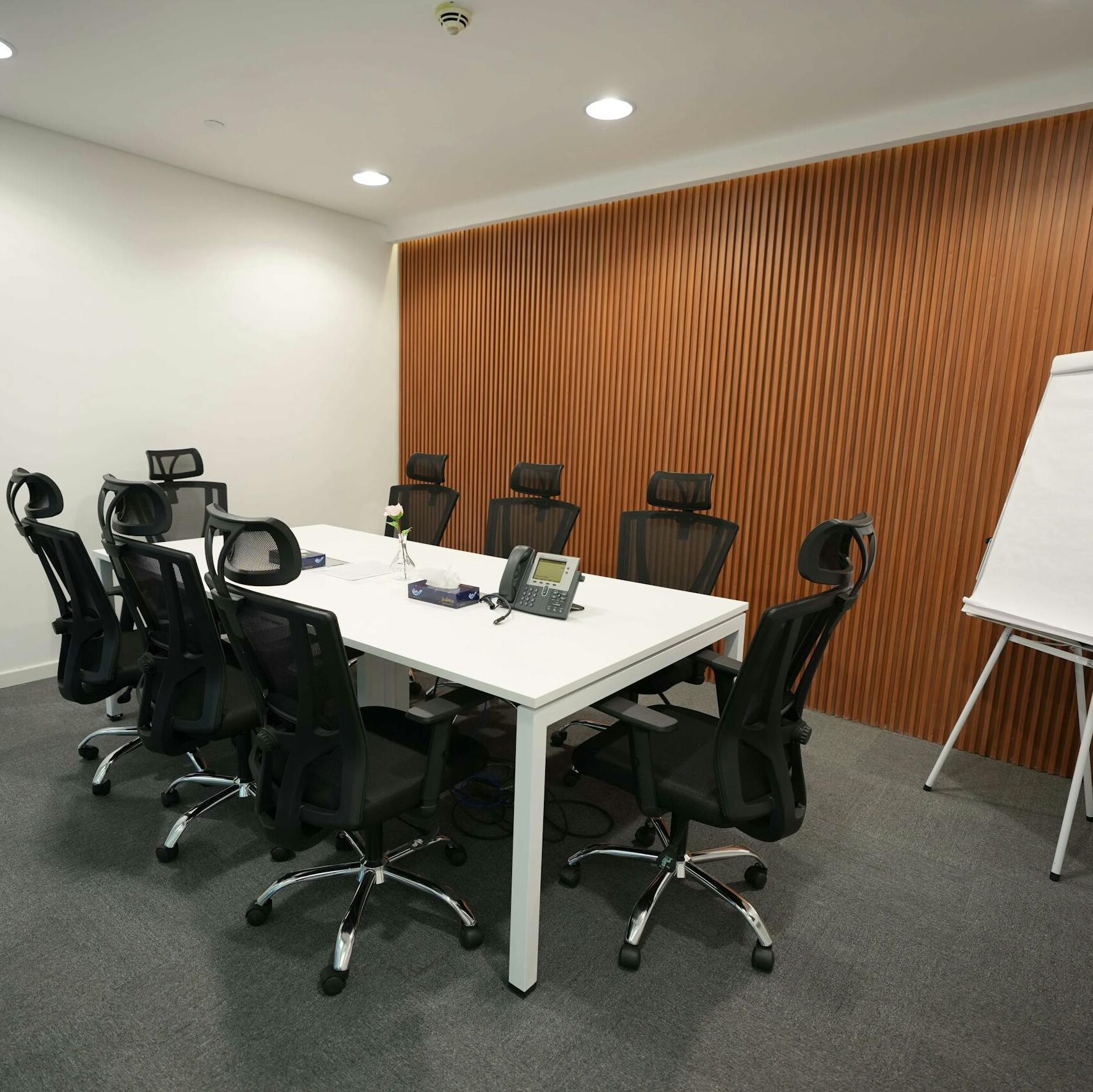 Spacious meeting room featuring ergonomic chairs, a large table, and a flip chart.